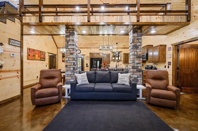 living room featuring wood walls, ornate columns, and high vaulted ceiling