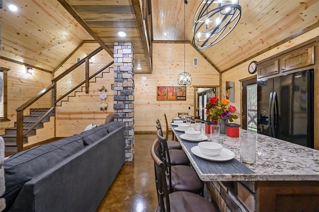 dining area with wood walls, high vaulted ceiling, wooden ceiling, and an inviting chandelier