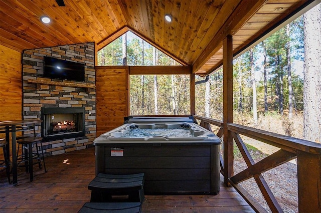 exterior space with an outdoor stone fireplace, a wooden deck, and a hot tub