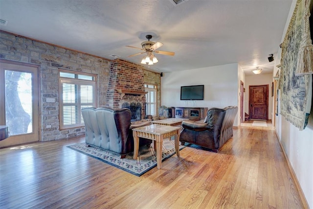 living room featuring ceiling fan, light hardwood / wood-style flooring, and a brick fireplace