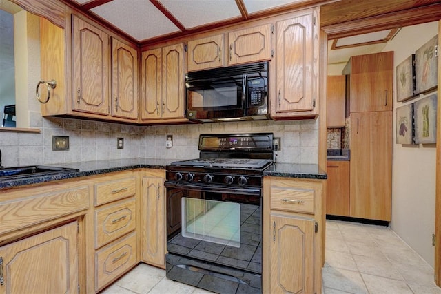 kitchen featuring decorative backsplash, dark stone counters, sink, black appliances, and light tile patterned floors