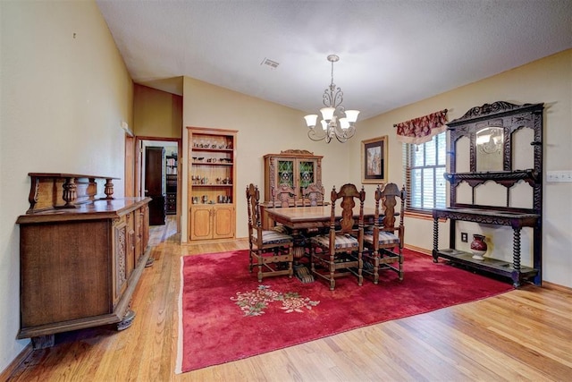 dining space featuring a chandelier, light wood-type flooring, and vaulted ceiling