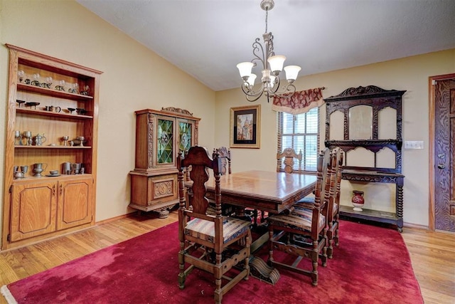 dining space with light hardwood / wood-style flooring, lofted ceiling, and an inviting chandelier