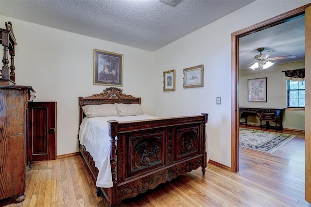 bedroom featuring ceiling fan, light hardwood / wood-style floors, and a textured ceiling