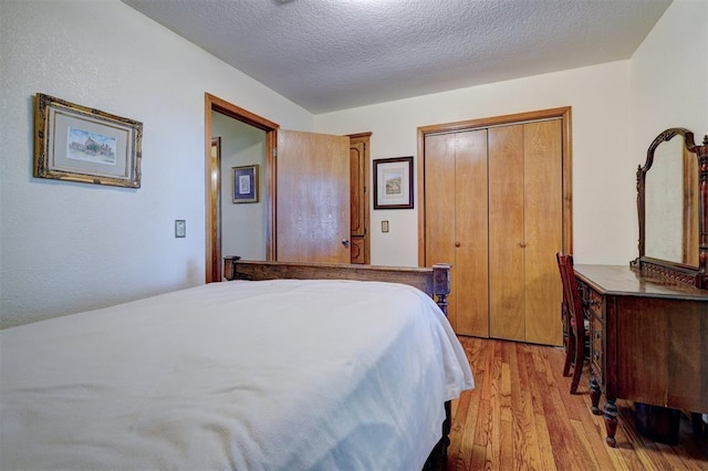 bedroom with a closet, light hardwood / wood-style floors, and a textured ceiling