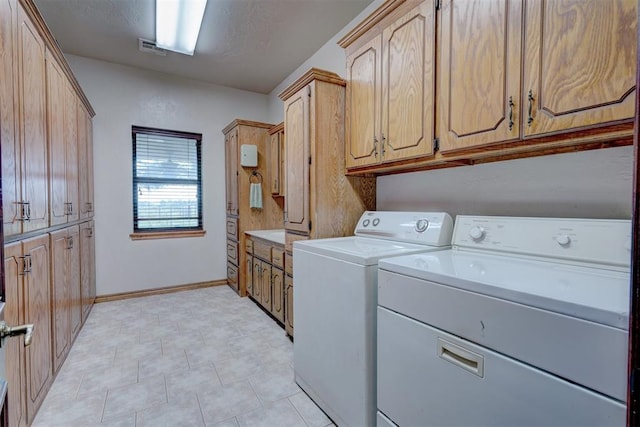 laundry room featuring washer and clothes dryer and cabinets