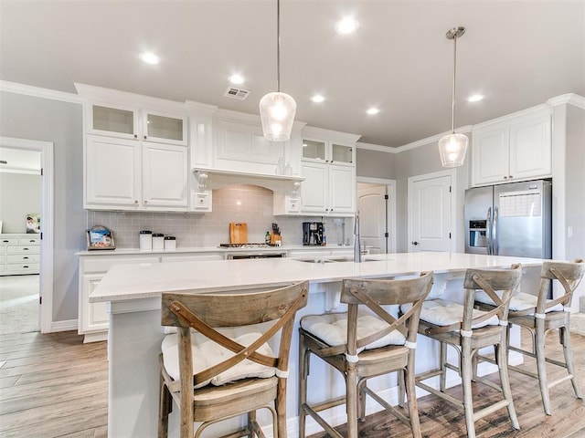 kitchen featuring white cabinets, sink, an island with sink, and pendant lighting