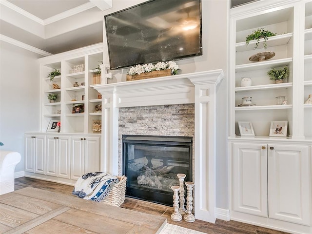 living room with crown molding, light wood-type flooring, and a fireplace