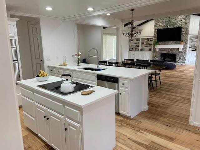 kitchen with a kitchen island with sink, sink, white cabinetry, and black electric stovetop