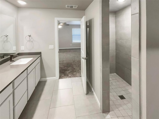 bathroom with tile patterned flooring, vanity, ceiling fan, and tiled shower