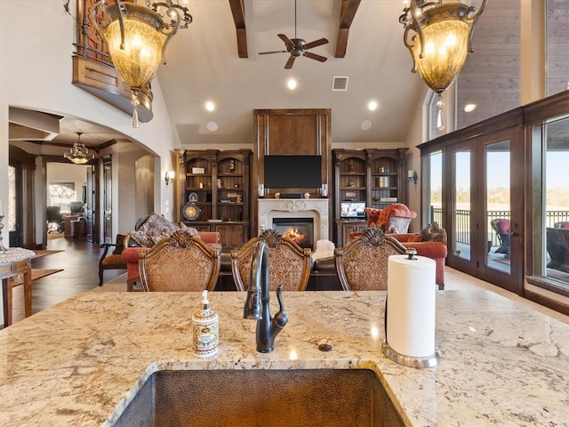 kitchen with high vaulted ceiling, sink, light stone countertops, dark wood-type flooring, and beam ceiling