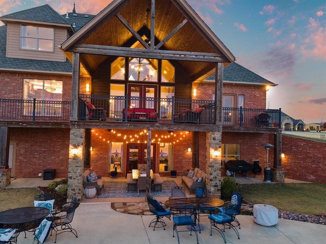 back house at dusk with a balcony and a patio area