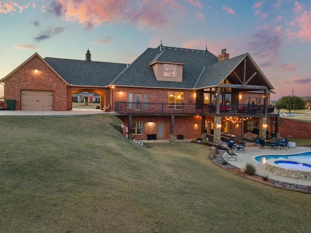 back house at dusk featuring a swimming pool with hot tub, a balcony, a yard, and a patio area