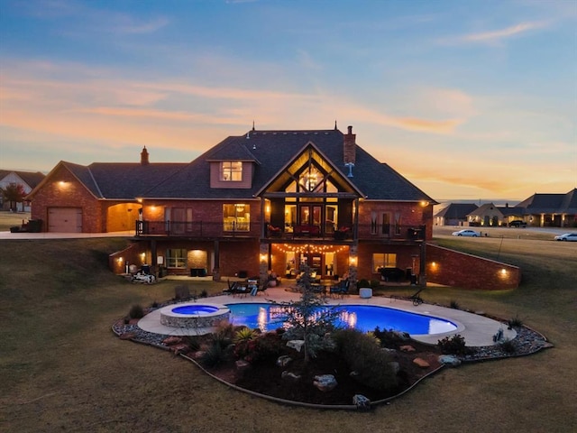 pool at dusk with a patio, an in ground hot tub, and a lawn