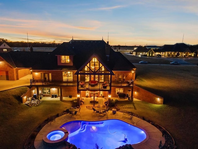 pool at dusk featuring an in ground hot tub and a patio