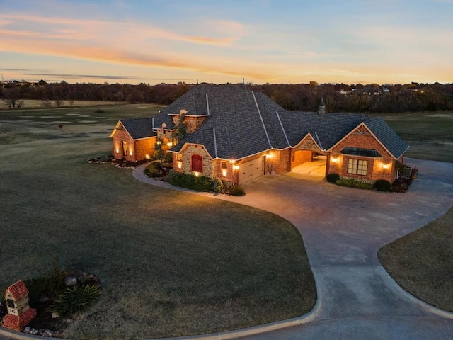 5451 Cottonwood Creek Cir, Norman, OK 73069 - view of front of home with an attached garage, concrete driveway, stone siding, a yard, and a chimney