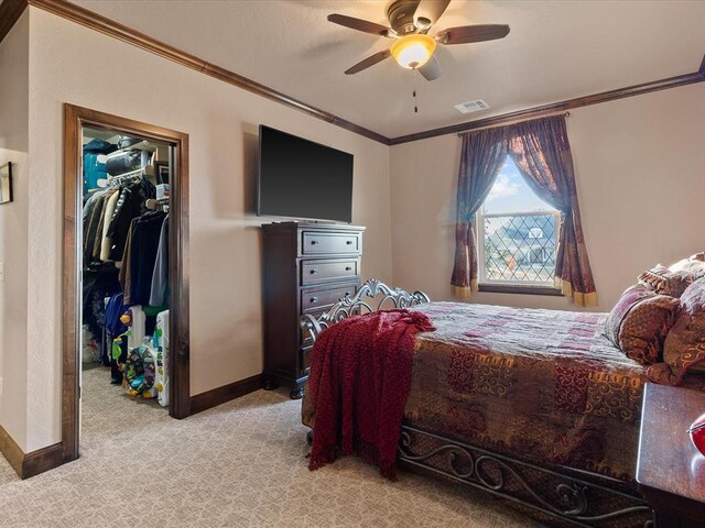 5451 Cottonwood Creek Cir, Norman, OK 73069 - bedroom featuring crown molding, a walk in closet, baseboards, light carpet, and a closet