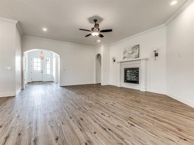 unfurnished living room with ceiling fan, light wood-type flooring, and crown molding