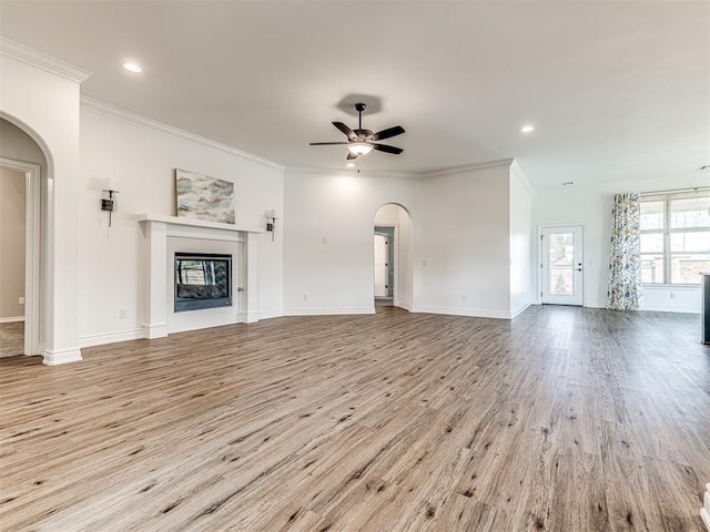 unfurnished living room with ceiling fan, ornamental molding, and light wood-type flooring