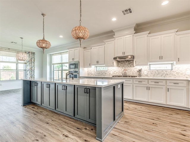 kitchen featuring white cabinets, pendant lighting, a center island with sink, and appliances with stainless steel finishes