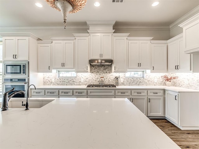 kitchen featuring crown molding, sink, decorative backsplash, appliances with stainless steel finishes, and white cabinetry