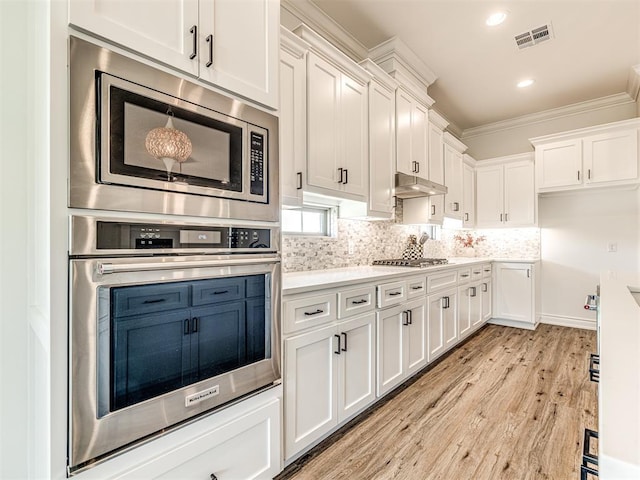 kitchen with white cabinets, decorative backsplash, light hardwood / wood-style floors, and appliances with stainless steel finishes