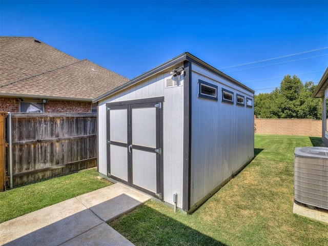 view of outdoor structure with central air condition unit and a yard