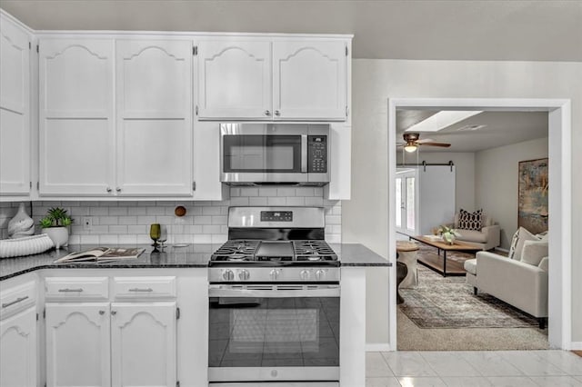 kitchen featuring dark stone counters, white cabinetry, appliances with stainless steel finishes, and tasteful backsplash