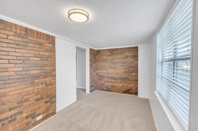 carpeted spare room with brick wall and ornamental molding