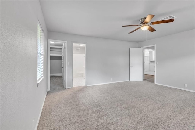 unfurnished bedroom featuring carpet flooring, ceiling fan, a walk in closet, and ensuite bath