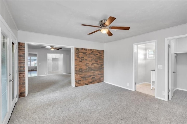 unfurnished room with light colored carpet, ceiling fan, and brick wall