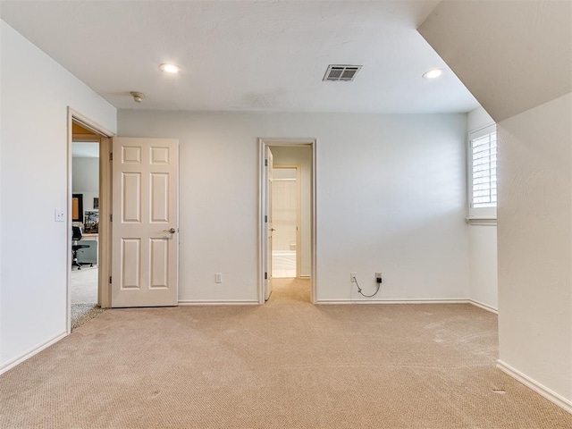 interior space with ensuite bathroom and light colored carpet