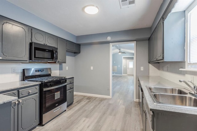 kitchen with stainless steel appliances, gray cabinets, light hardwood / wood-style floors, and sink