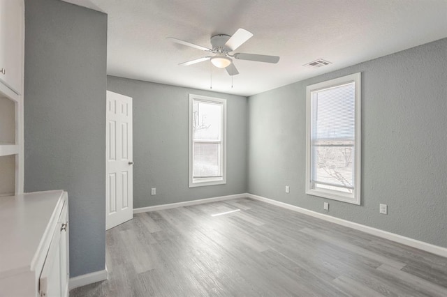 empty room with ceiling fan and light wood-type flooring