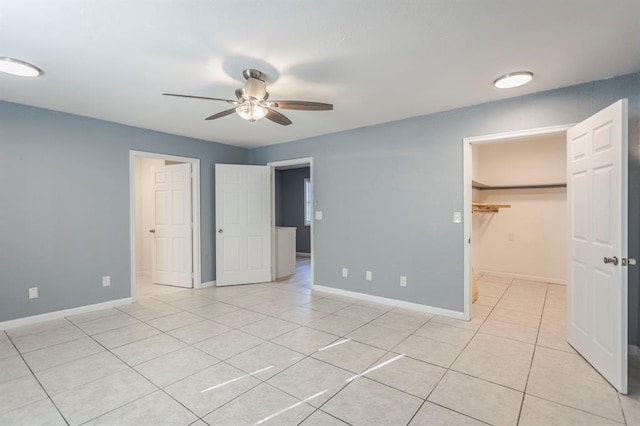 unfurnished bedroom with a walk in closet, light tile patterned floors, ceiling fan, and a closet