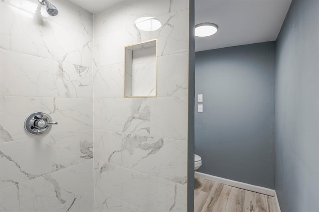 bathroom with hardwood / wood-style flooring, a tile shower, and toilet