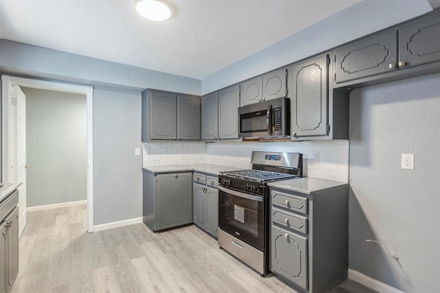 kitchen featuring stainless steel appliances, gray cabinets, and backsplash