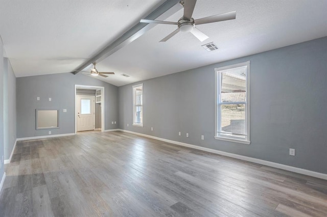 unfurnished room featuring hardwood / wood-style floors, a wealth of natural light, lofted ceiling with beams, and ceiling fan