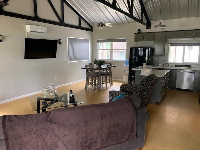 living room featuring a wall unit AC, ceiling fan, sink, and high vaulted ceiling