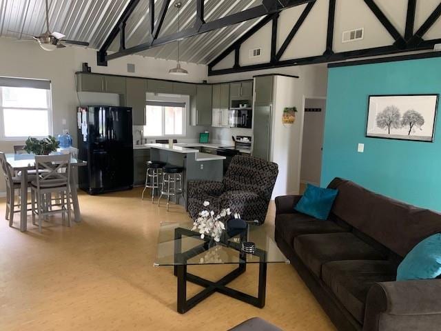 living room featuring ceiling fan, beam ceiling, and high vaulted ceiling