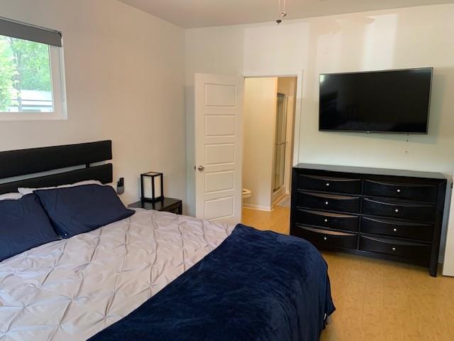 bedroom with ensuite bath and light wood-type flooring