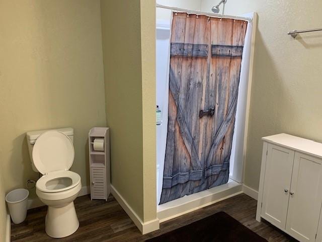 bathroom with hardwood / wood-style flooring, curtained shower, and toilet