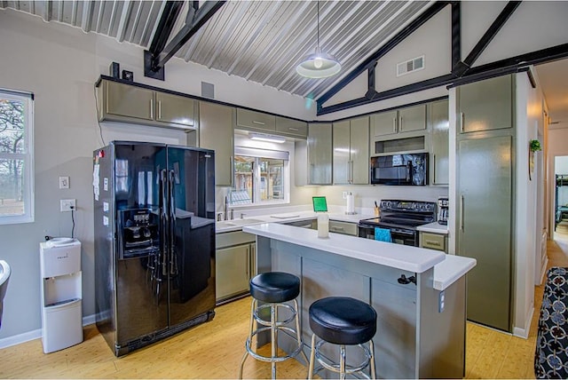 kitchen with a breakfast bar area, gray cabinetry, lofted ceiling with beams, black appliances, and light wood-type flooring