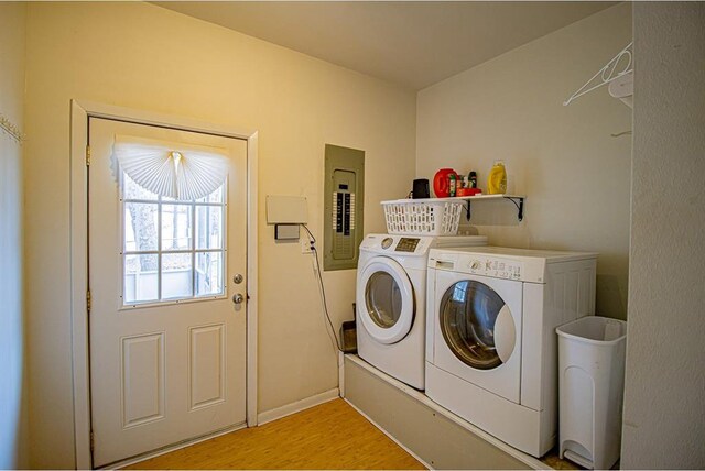 laundry area featuring separate washer and dryer, electric panel, and light hardwood / wood-style flooring