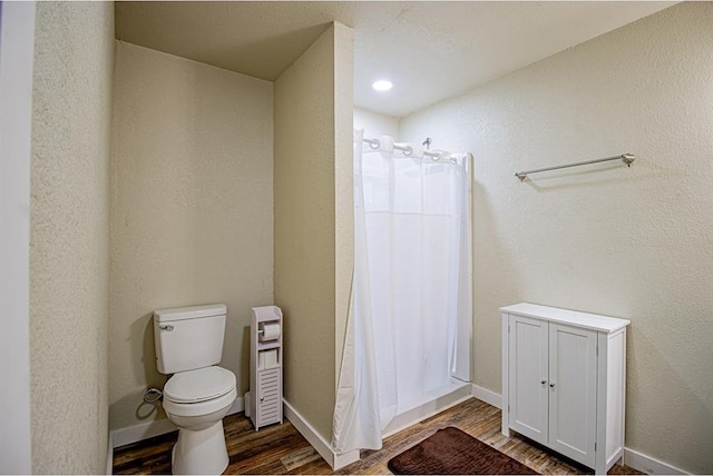 bathroom featuring hardwood / wood-style flooring, toilet, and curtained shower