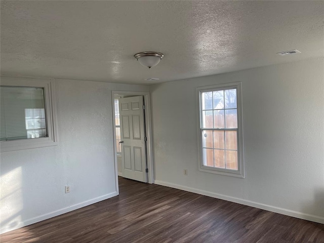 unfurnished room with dark hardwood / wood-style flooring and a textured ceiling