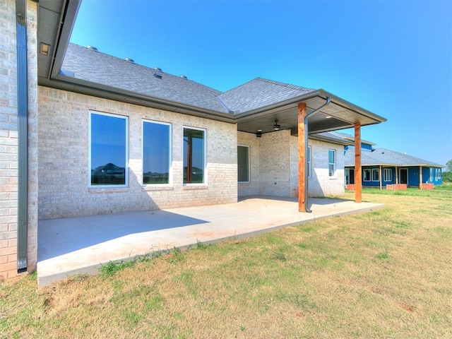 rear view of house featuring a yard, ceiling fan, and a patio area