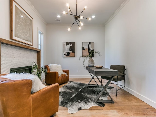 office space with ornamental molding, an inviting chandelier, a brick fireplace, and light hardwood / wood-style flooring