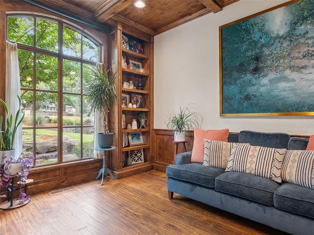 sitting room with beam ceiling, ornamental molding, wood walls, and hardwood / wood-style floors