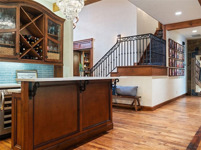 bar with backsplash, light hardwood / wood-style flooring, beverage cooler, and a chandelier